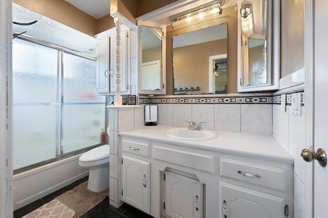 full bathroom with vanity, bath / shower combo with glass door, tile patterned flooring, decorative backsplash, and tile walls