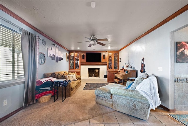 carpeted living room featuring a fireplace, ceiling fan, and crown molding