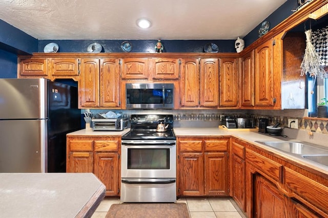 kitchen featuring light tile patterned flooring, sink, and stainless steel appliances