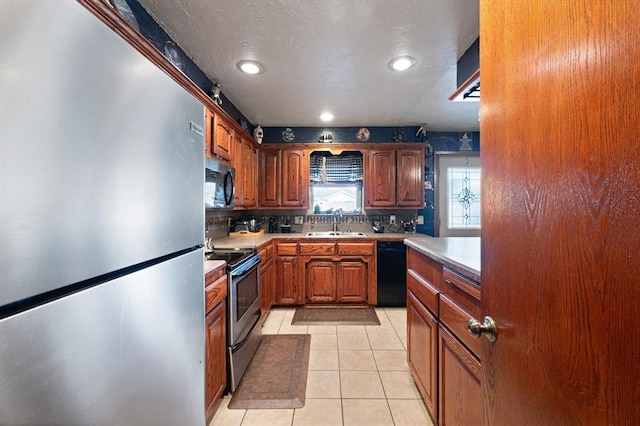 kitchen with light tile patterned floors, sink, backsplash, and black appliances