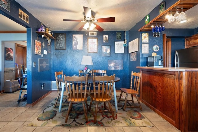 dining room featuring ceiling fan, light tile patterned floors, and a textured ceiling