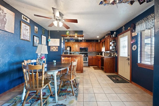 tiled dining area with a textured ceiling and ceiling fan