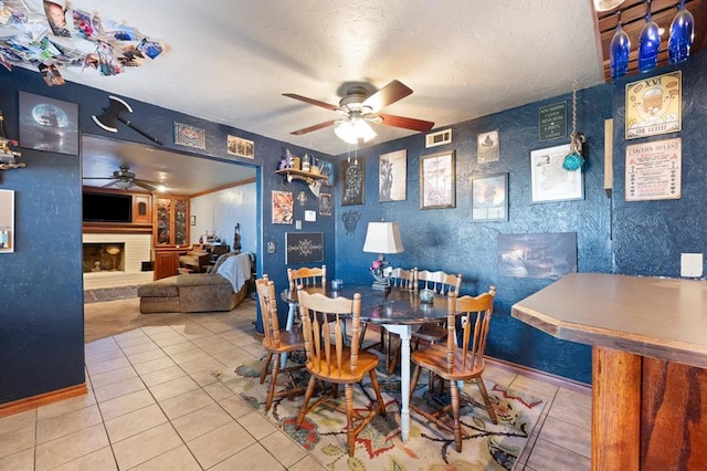 tiled dining space featuring a fireplace and ceiling fan