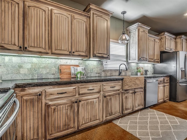 kitchen with sink, stainless steel appliances, hanging light fixtures, tasteful backsplash, and dark tile patterned floors