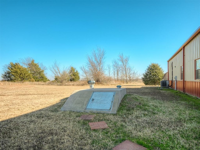 entry to storm shelter featuring a lawn and central air condition unit