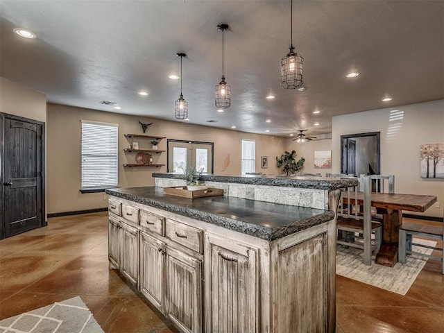 kitchen with pendant lighting, recessed lighting, visible vents, a kitchen island, and baseboards