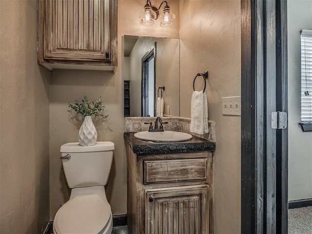 half bathroom with toilet, a textured wall, and vanity