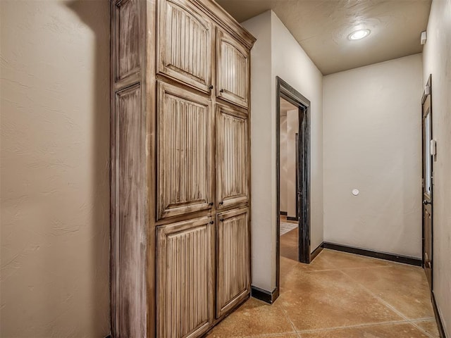 corridor featuring a textured wall and baseboards