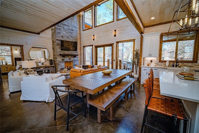 dining room with a stone fireplace, wood ceiling, and high vaulted ceiling