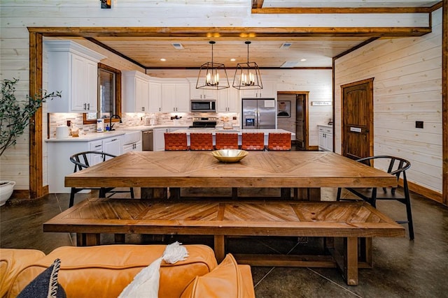 dining room featuring sink, an inviting chandelier, and wood walls