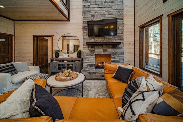 living room with a stone fireplace, wood ceiling, and wooden walls