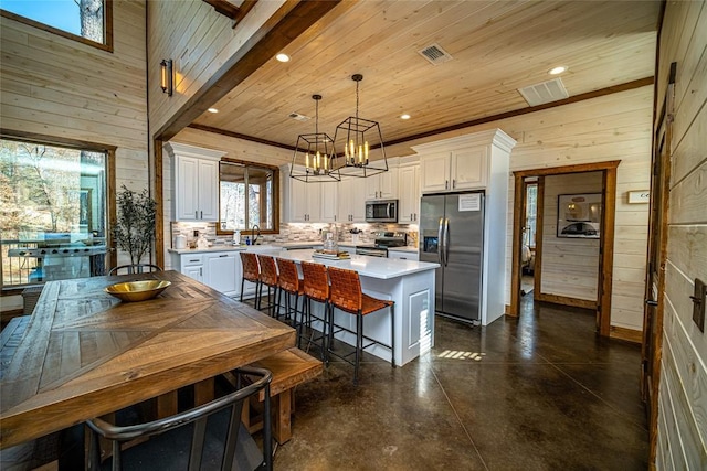 kitchen with a center island, white cabinets, decorative light fixtures, and appliances with stainless steel finishes