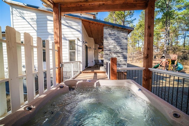 view of patio with a playground and a hot tub