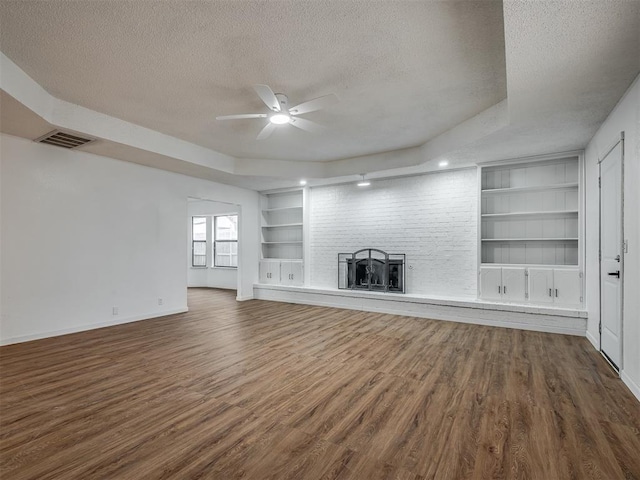 unfurnished living room with a textured ceiling, a tray ceiling, ceiling fan, and dark wood-type flooring