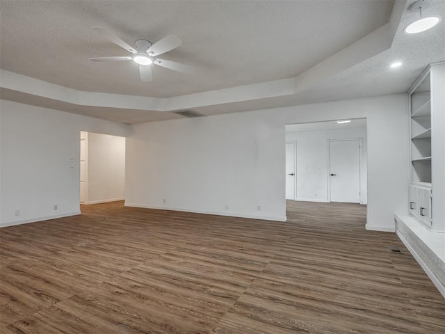 empty room featuring built in shelves, ceiling fan, dark hardwood / wood-style floors, and a textured ceiling