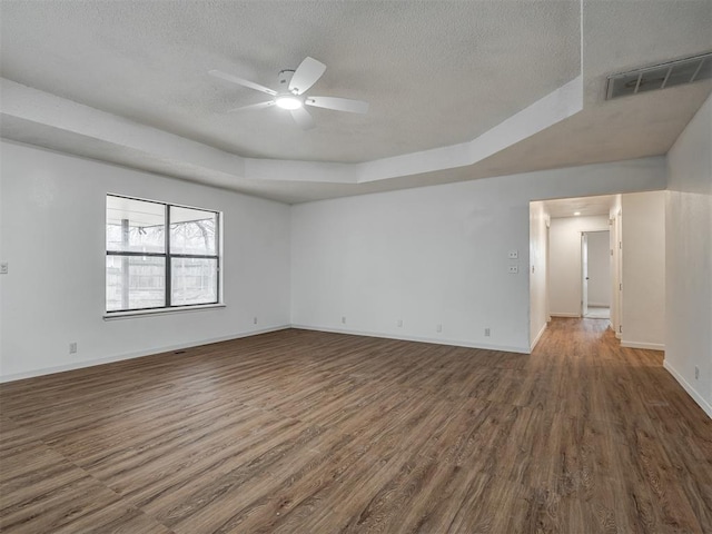 spare room with dark hardwood / wood-style floors, ceiling fan, a raised ceiling, and a textured ceiling