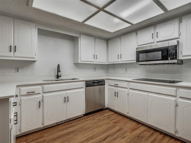 kitchen featuring appliances with stainless steel finishes, hardwood / wood-style flooring, white cabinetry, and sink