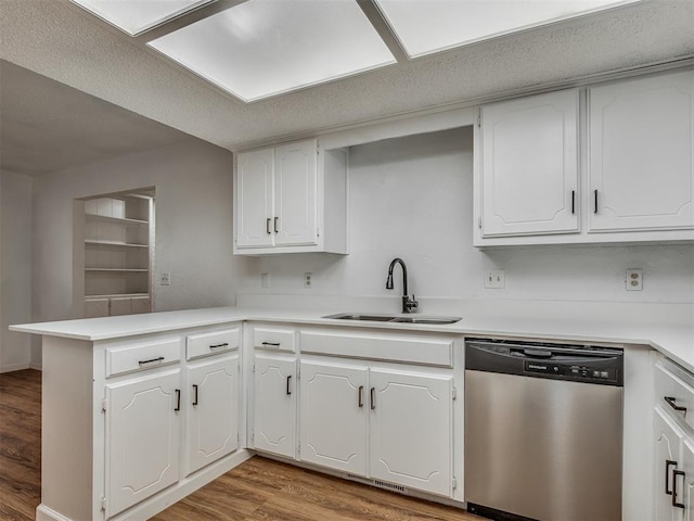 kitchen with kitchen peninsula, white cabinets, sink, dishwasher, and hardwood / wood-style floors