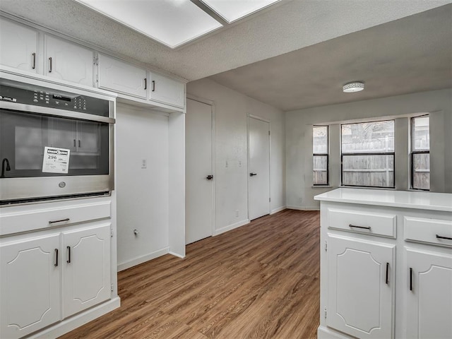 kitchen with white cabinetry, stainless steel oven, and light hardwood / wood-style floors