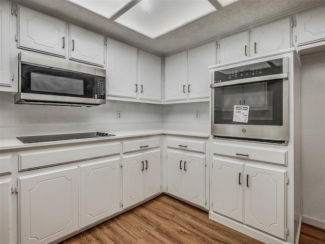 kitchen featuring appliances with stainless steel finishes, light hardwood / wood-style flooring, and white cabinetry