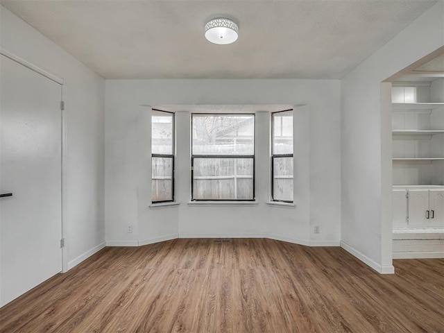 empty room featuring built in shelves and light wood-type flooring