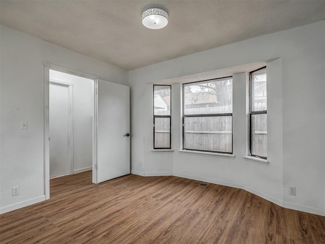 unfurnished room with a textured ceiling and hardwood / wood-style flooring