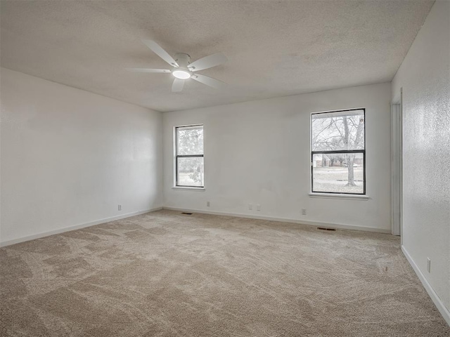 spare room with ceiling fan, light colored carpet, and a textured ceiling