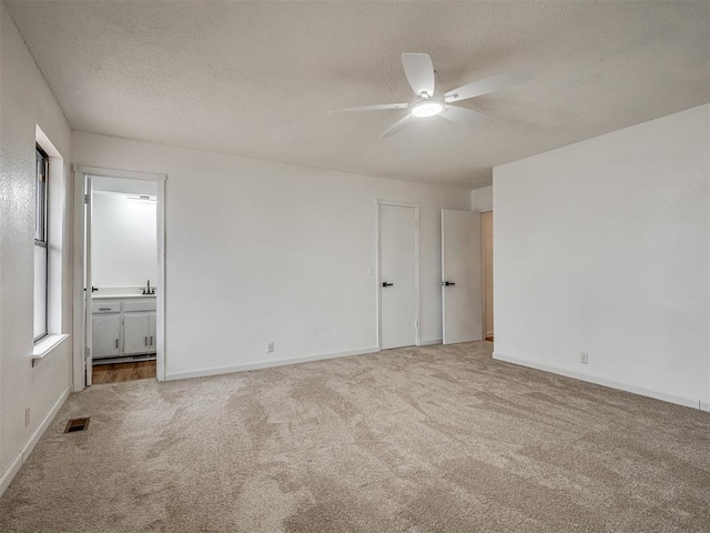 carpeted spare room featuring ceiling fan and a textured ceiling