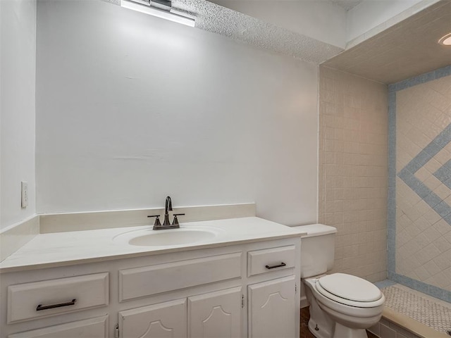 bathroom featuring tiled shower, vanity, and toilet