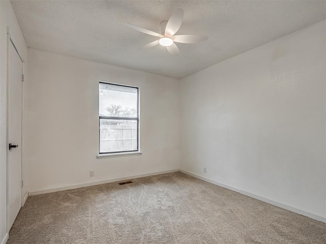 empty room featuring ceiling fan, carpet floors, and a textured ceiling