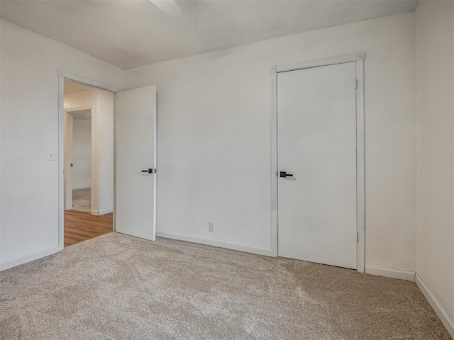 unfurnished bedroom with ceiling fan, light colored carpet, and a closet