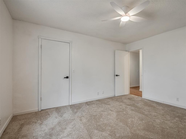 spare room with a textured ceiling, ceiling fan, and light carpet