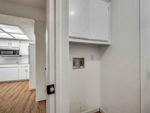 washroom with washer hookup and light hardwood / wood-style flooring