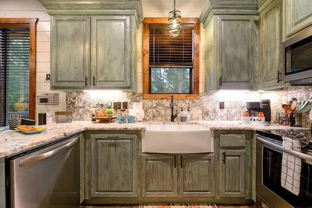 kitchen with appliances with stainless steel finishes, backsplash, light stone counters, and sink