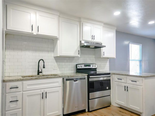 kitchen with appliances with stainless steel finishes, sink, white cabinets, and light hardwood / wood-style flooring