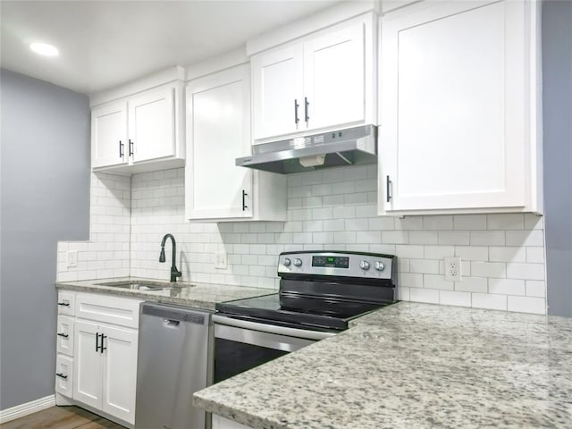 kitchen featuring appliances with stainless steel finishes, sink, white cabinets, backsplash, and light stone countertops