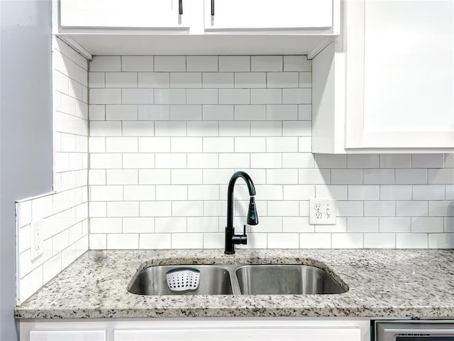 kitchen featuring sink, white cabinets, and light stone counters