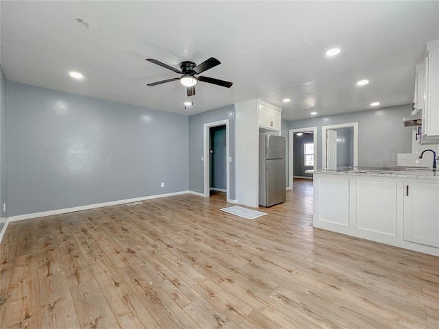 interior space with stainless steel refrigerator, white cabinets, ceiling fan, light hardwood / wood-style floors, and light stone countertops