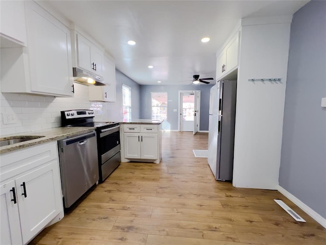 kitchen featuring white cabinetry, light wood-type flooring, appliances with stainless steel finishes, kitchen peninsula, and backsplash