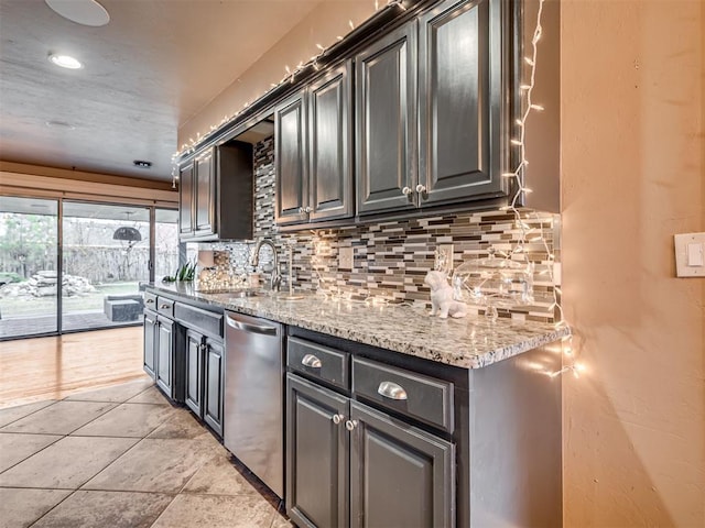 kitchen with light stone countertops, dishwasher, sink, backsplash, and light tile patterned floors