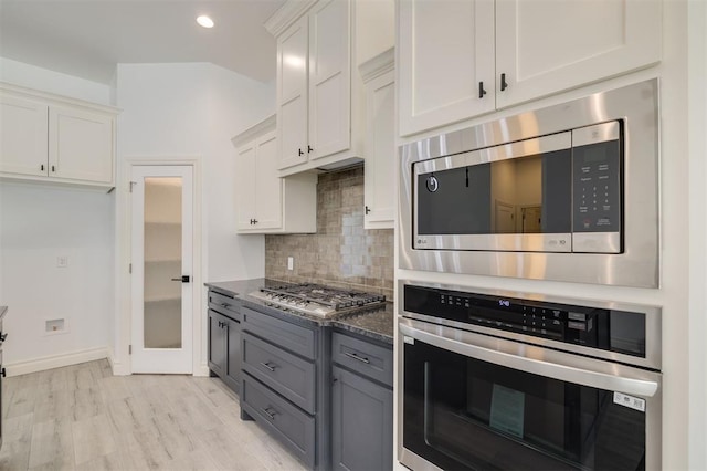 kitchen featuring appliances with stainless steel finishes, gray cabinets, white cabinetry, and tasteful backsplash