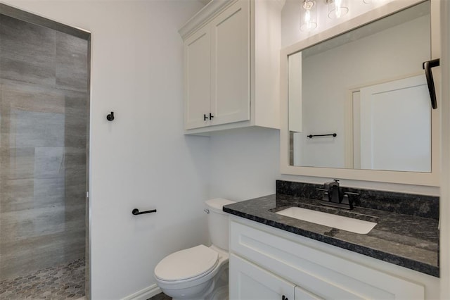 bathroom with tiled shower, vanity, and toilet