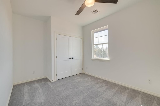 unfurnished bedroom featuring a closet, light colored carpet, and ceiling fan