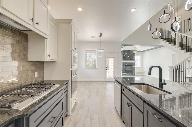 kitchen featuring sink, decorative light fixtures, gray cabinetry, and dark stone countertops