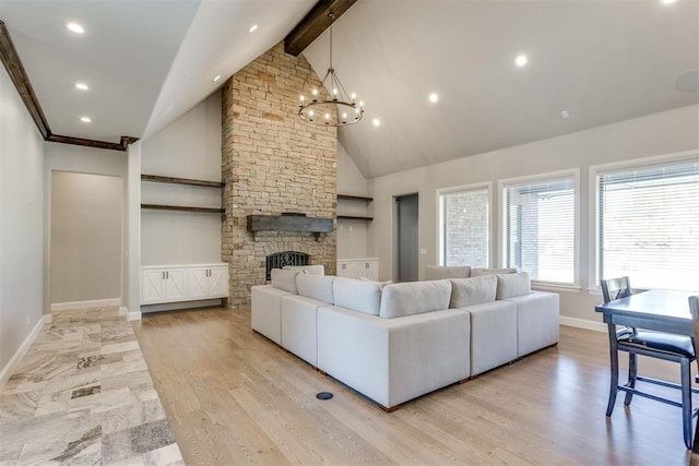 living room featuring a chandelier, beam ceiling, a fireplace, and light hardwood / wood-style flooring