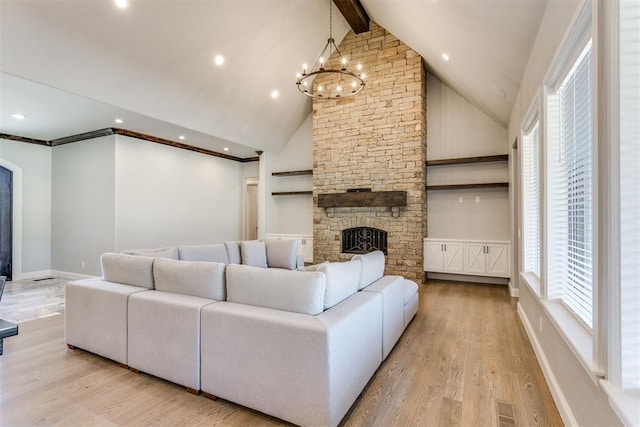 living room with a notable chandelier, lofted ceiling with beams, light hardwood / wood-style floors, and a stone fireplace