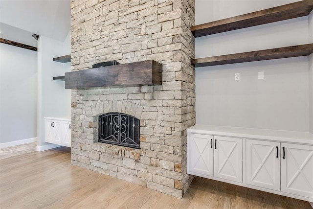 unfurnished living room with a stone fireplace and light wood-type flooring