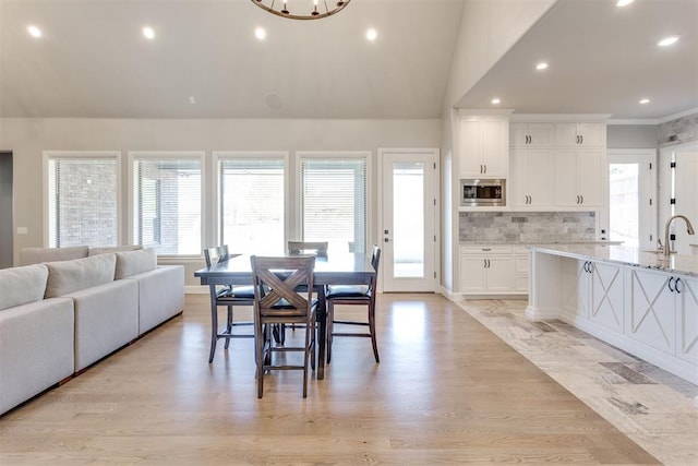 dining room featuring light hardwood / wood-style floors, an inviting chandelier, sink, and vaulted ceiling