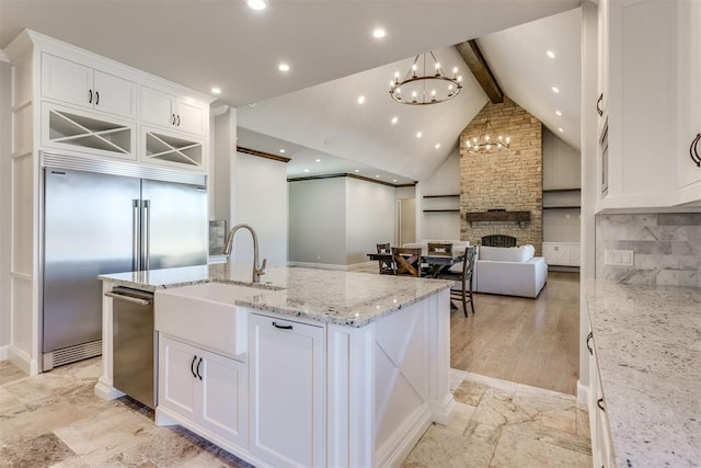 kitchen with white cabinets, tasteful backsplash, stainless steel appliances, beamed ceiling, and a stone fireplace