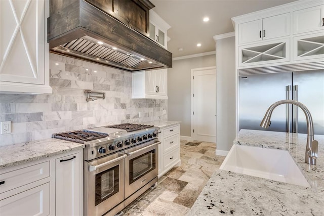 kitchen featuring premium range hood, high quality appliances, white cabinetry, and sink